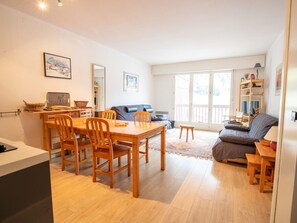 A spacious living area with a dining table, chairs, a sofa, and a large window. - Spacious apartment at the foot of ski slopes - 8 guests (Villarodin-Bourget)