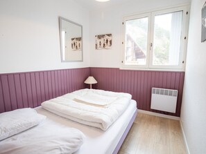 A bedroom with a bed, a window, a wall-mounted heater, and a mirror. - Spacious apartment at the foot of ski slopes - 8 guests (Villarodin-Bourget)