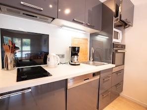 A modern kitchen with stainless steel appliances, a coffee maker, and utensils in a jar. - Spacious apartment at the foot of ski slopes - 8 guests (Villarodin-Bourget)