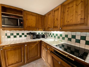A kitchen with wooden cabinets, a microwave, a coffee maker, and a sink. - Comfortable apartment mountain view - 8 guests (Méribel)