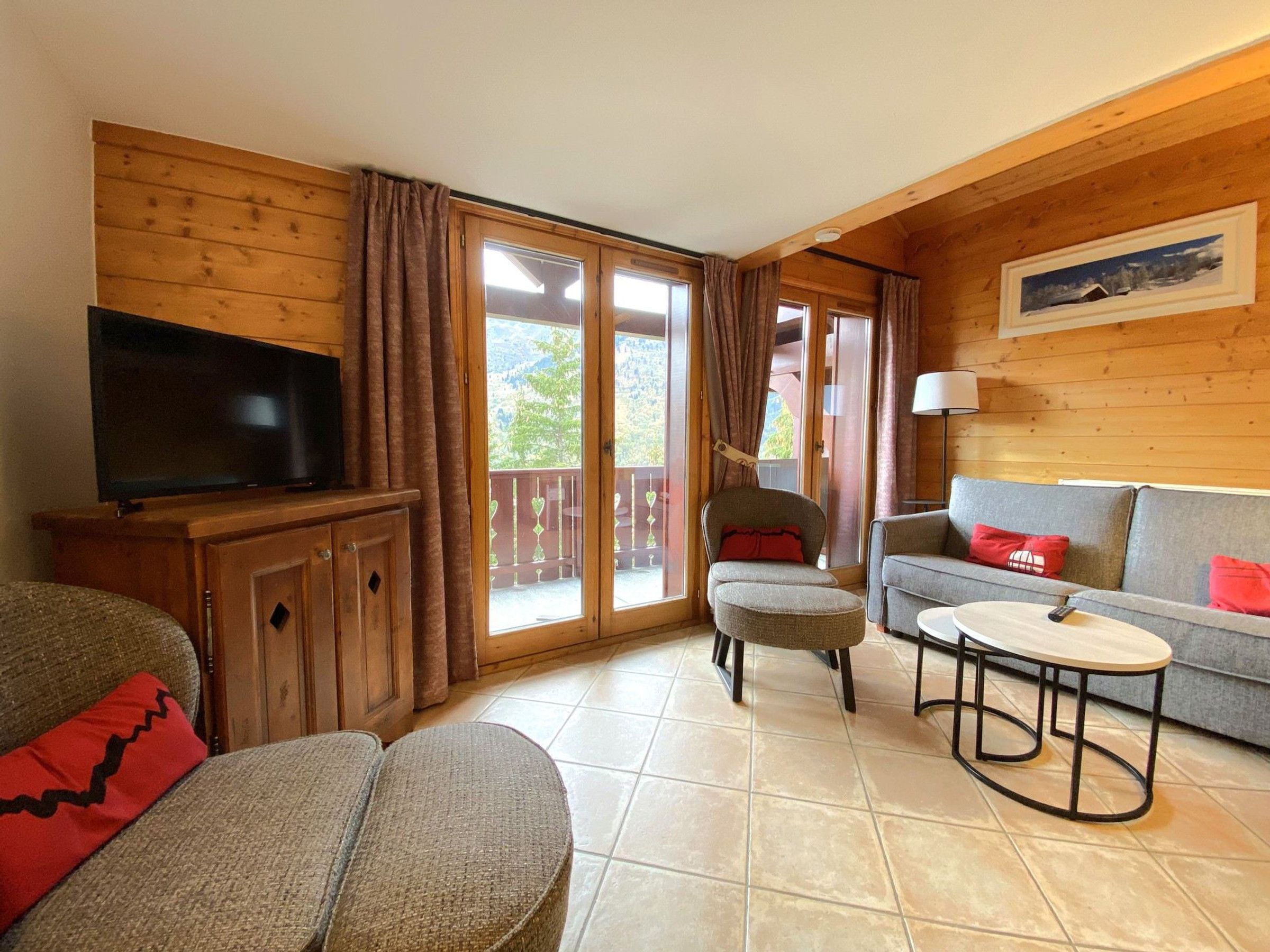 A furnished living room with a television, sofa, armchair, and a small table.