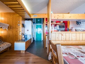 A cozy cabin interior with a wooden floor, a kitchenette, a dining area, and a sleeping space. - Apartment near slopes - 6 guests (Bourg-Saint-Maurice)