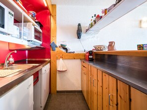 A compact kitchen with a microwave, oven, and sink. There are wooden cabinets and a countertop. - Apartment near slopes - 6 guests (Bourg-Saint-Maurice)