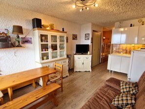 A cozy living room with a wooden table, a sofa, and a television. - South studio, pets welcome - 6 guests (Saint-Michel-de-Chaillol)