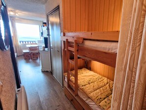 A bunk bed room with a wooden headboard, a small desk, and a view of the outdoors. - South studio, pets welcome - 6 guests (Saint-Michel-de-Chaillol)