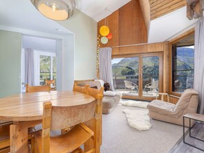 A spacious living area with a wooden dining table, comfortable seating, and a large sliding glass door leading to a balcony with a mountain view. - Apartment with fireplace, mountain view - 8 guests (Avoriaz)