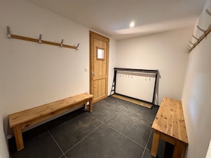 A room with a wooden bench, a small table, a door, and a wall-mounted rack. - Large chalet - 16 guests (Vars)