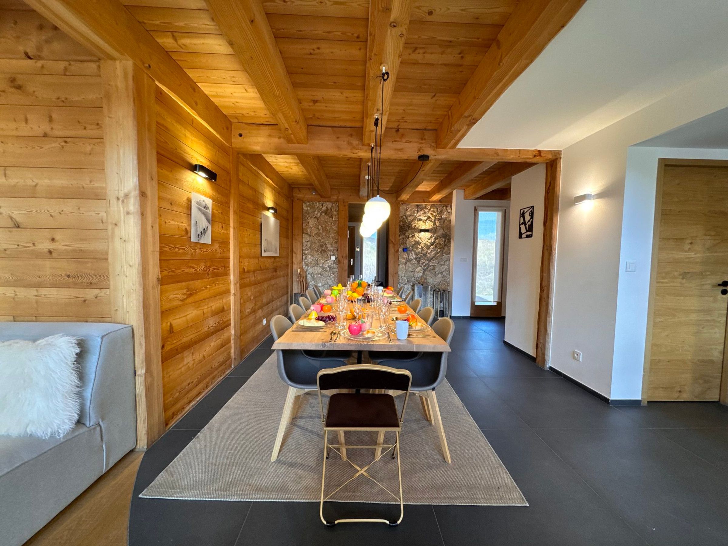 Een houten interieur met een eettafel gedekt voor zes personen, een bank en een stenen muur.