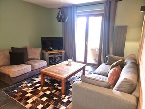 A living room with a sofa, a coffee table, and a television. - Apartment with parking and pets - 6 guests (Les Gets)