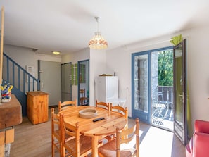 A dining area with a round wooden table, chairs, and a hanging light fixture. - Cozy duplex apartment with view - 6 guests (Esquièze-Sère)