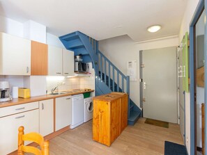 Eine kleine Küche mit einer Holzeinrichtung, einer Waschmaschine und einer blauen Treppe.