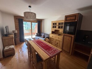 Cozinha acolhedora com armários de madeira, mesa de jantar com cadeiras e uma janela grande com cortinas.