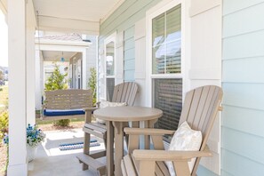 A covered porch with a bench, two chairs, and a table. - Beau Coast Retreat | Pool + Near Waterfront (Beaufort)