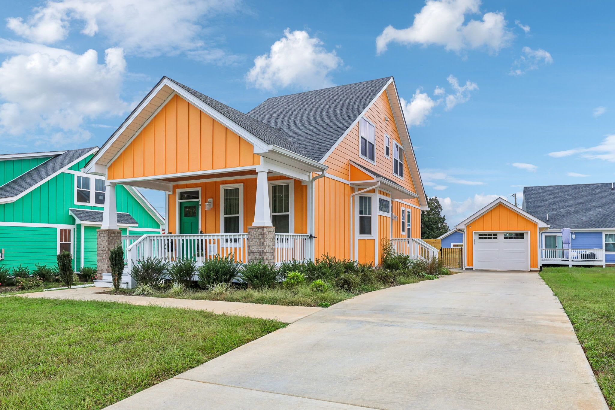 A residential area with houses featuring a modern architectural style, a well-maintained lawn, and a clear sky.