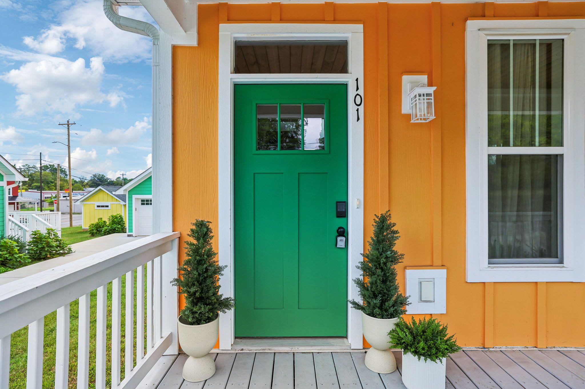 A house with a green door, a white porch railing, and a small window.