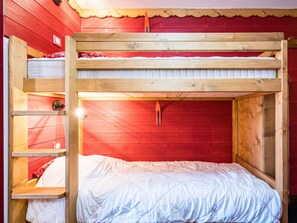 Un lit superposé avec une structure en bois et un mur rouge.