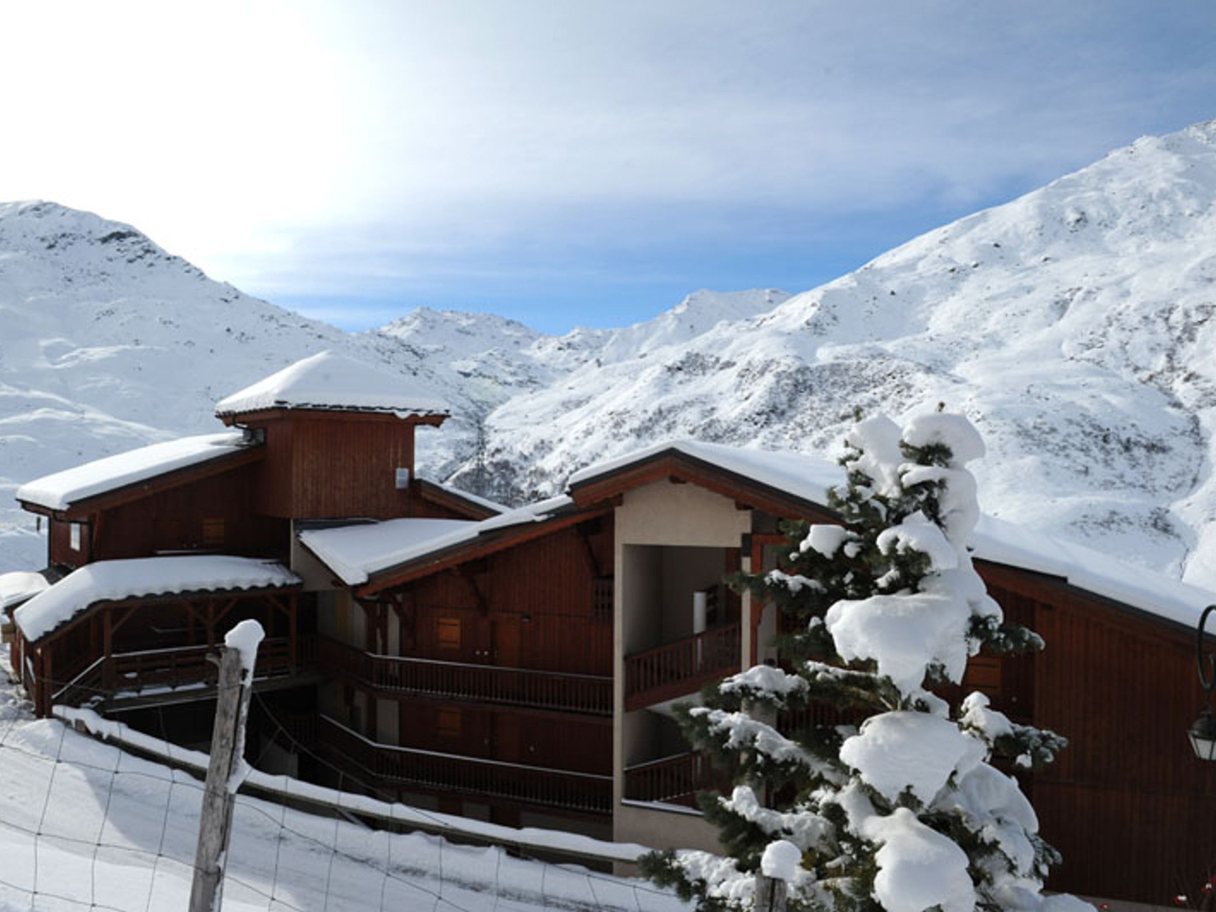 Una cabaña de madera con balcón, rodeada de montañas nevadas.