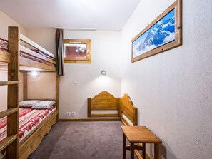A compact room with bunk beds, a small desk, and a framed picture on the wall. - Spacious apartment at the slopes - 5 guests (Les Menuires)