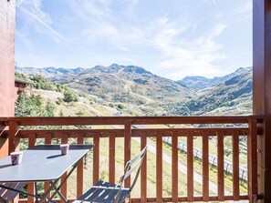 A balcony with a table and chairs, overlooking a mountainous landscape. - Spacious apartment at the slopes - 5 guests (Les Menuires)