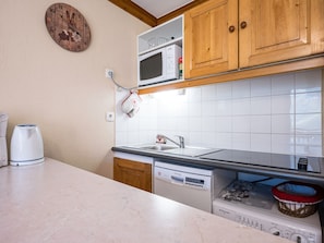 A compact kitchen with a microwave, oven, and dishwasher. - Spacious apartment at the slopes - 5 guests (Les Menuires)