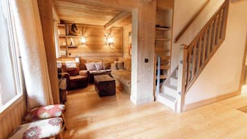 A wooden interior with a staircase, a sofa, and a coffee table.
