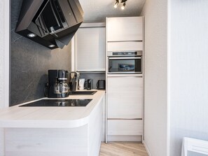 A compact kitchen with a built-in oven, a coffee maker, and a microwave. - Comfortable apartment with mountain view - 4 guests (Les Menuires)
