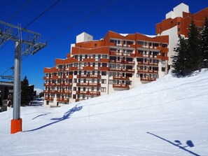 A multi-story hotel with balconies and a ski slope in the background. - Comfortable apartment with mountain view - 4 guests (Les Menuires)