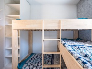 A bunk bed with a wooden frame, a lower bunk with a patterned blanket, and a headboard against a wall. - Comfortable apartment with mountain view - 4 guests (Les Menuires)