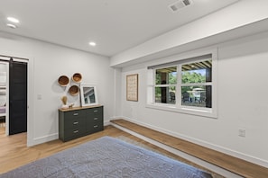 A spacious room with a large window, a dark-colored dresser, and a patterned rug. - The Treehouse, Sleeps 12, Waterfront, Game Room, Firepit, Kayaks + MORE! (Milledgeville)