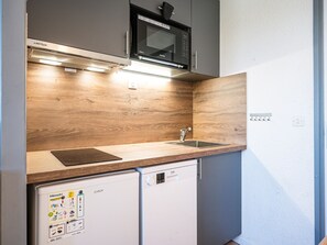 A compact kitchen with a microwave, a dishwasher, and a sink. - Pleasant apartment, near slopes - 4 guests (Les Menuires)