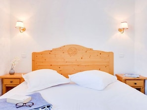 A neatly made bed with white linens, two bedside lamps, a wooden headboard, and a small bedside table with a vase of flowers. - Ski-in ski-out chalet - 4 guests (Les Menuires)