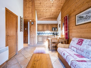 A wooden interior with a kitchen, dining area, and a sofa with patterned upholstery. - Spacious apartment - 6 guests (Les Menuires)