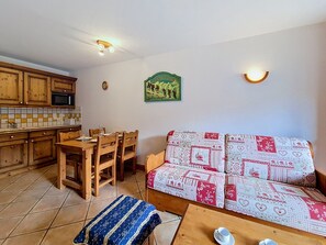 Ein gemütlicher Wohnbereich mit einer Couch, einem Esstisch und einer Küche im Hintergrund.