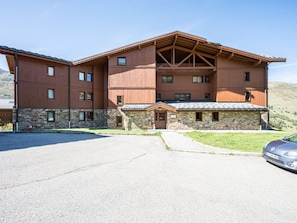 A multi-story building with a stone facade and a wooden upper structure. - Renovated studio cabin, mountain view (Les Menuires)