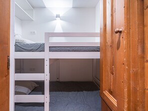 A bunk bed room with a wooden wardrobe and a ceiling light fixture. - Renovated studio cabin, mountain view (Les Menuires)