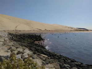 Eine Küstenlandschaft mit felsigem Ufer, Sandstrand und blauem Himmel.