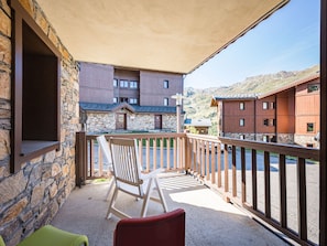 A balcony with a stone wall, a wooden railing, and a view of a mountain. - Cozy apartment in Les Menuires - 4 guests (Les Menuires)