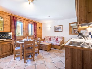 A wooden interior with a dining area, a sofa, a kitchen, and a television. - Cozy apartment in Les Menuires - 4 guests (Les Menuires)
