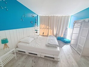 A bedroom with a bed, a window with curtains, a white wardrobe, and a shelf with decorative items. - Charming duplex near beach - 6 guests (Cabourg)
