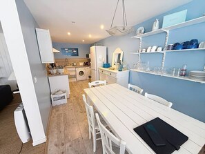 A compact kitchen with a dining area, a washing machine, and a refrigerator. - Charming duplex near beach - 6 guests (Cabourg)