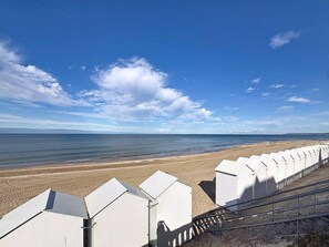 A beach with a row of white structures, possibly beach huts, and a clear sky. - Charming duplex near beach - 6 guests (Cabourg)