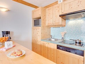 A kitchen with wooden cabinets, a blue tiled backsplash, a stainless steel sink, and a dishwasher. - Spacious ski-in/ski-out apartment - 7 guests (Les Menuires)