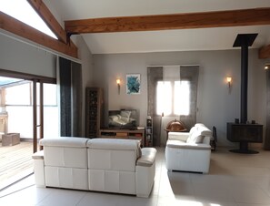 A modern living room with a sofa, a television, a fireplace, and a large window.