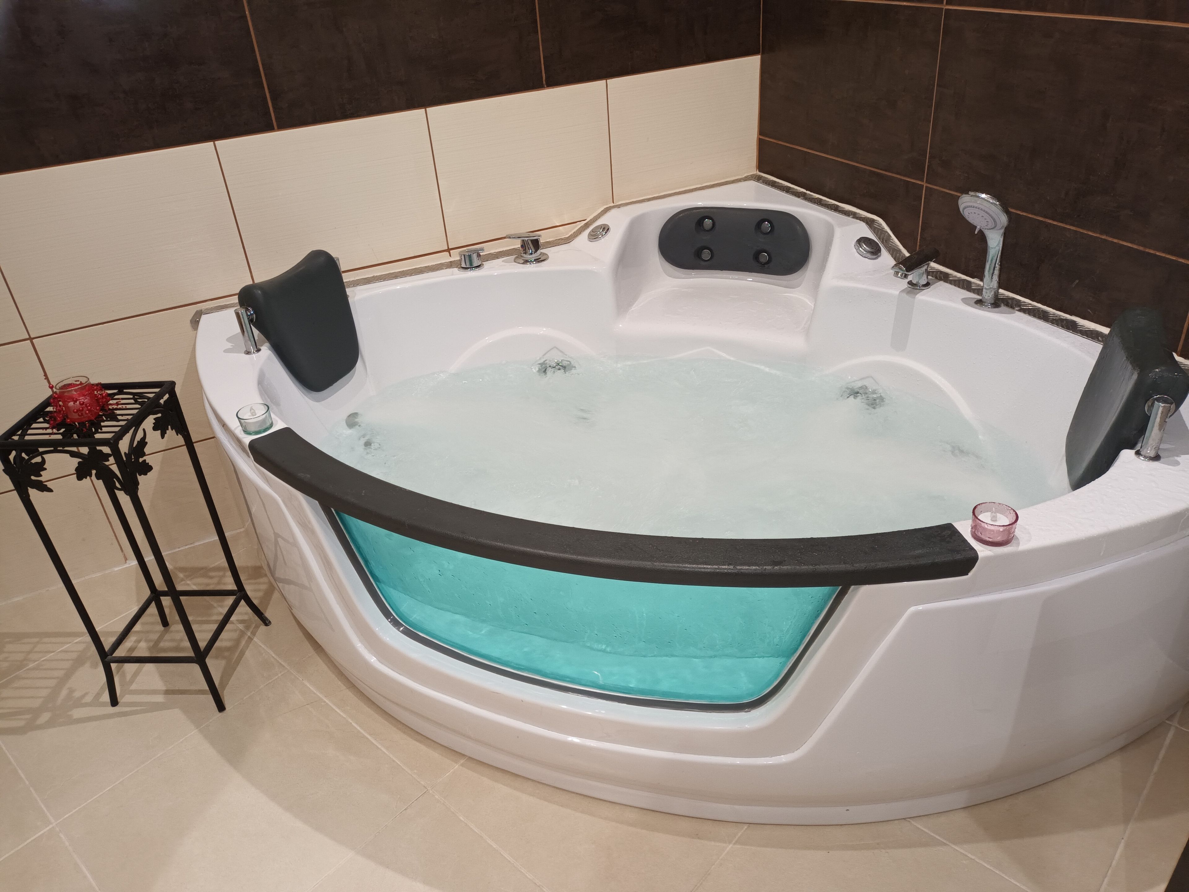 Un bain à remous doté d’un panneau de commande et d’une petite table sur laquelle est posée une bougie.