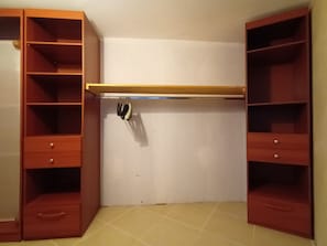 A room with a built-in closet featuring multiple shelves and drawers.