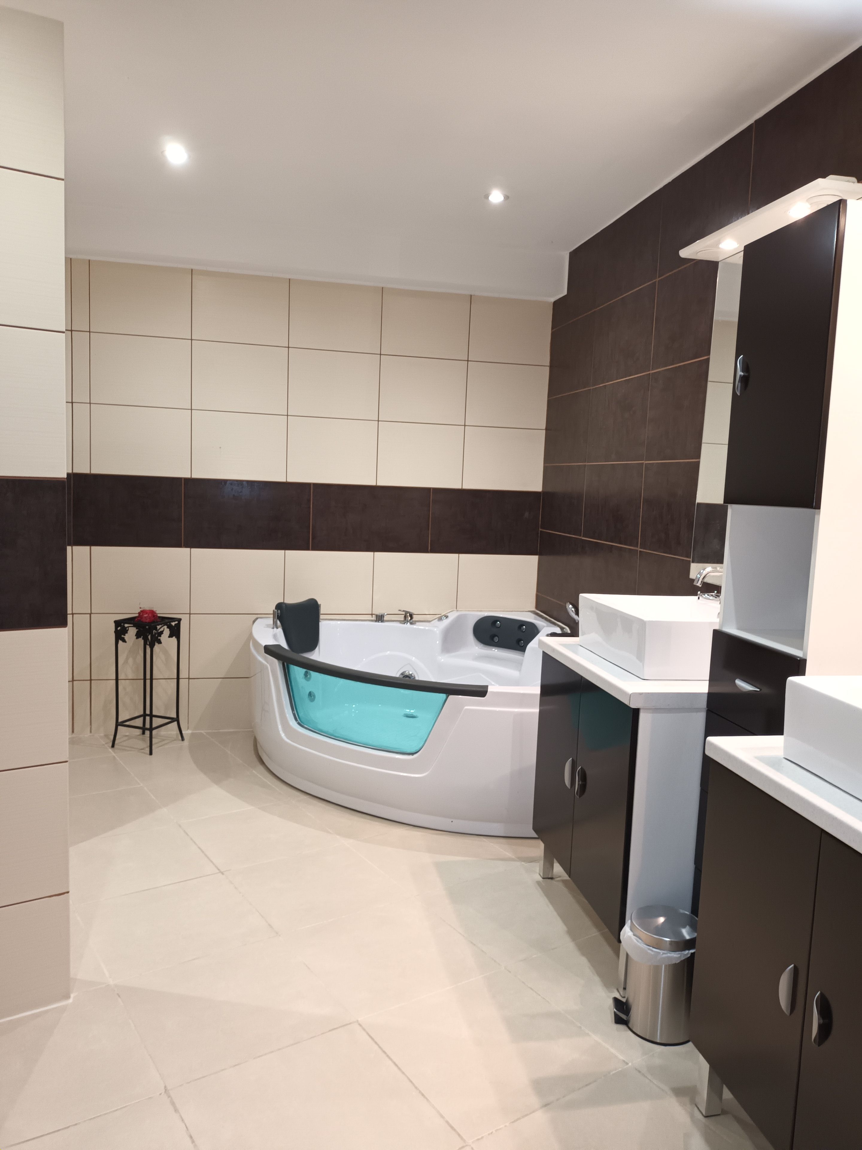 Un baño moderno con una bañera independiente, un tocador con espejo y un taburete pequeño.