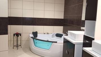 Un baño moderno con una bañera independiente, un tocador con espejo y un taburete pequeño.