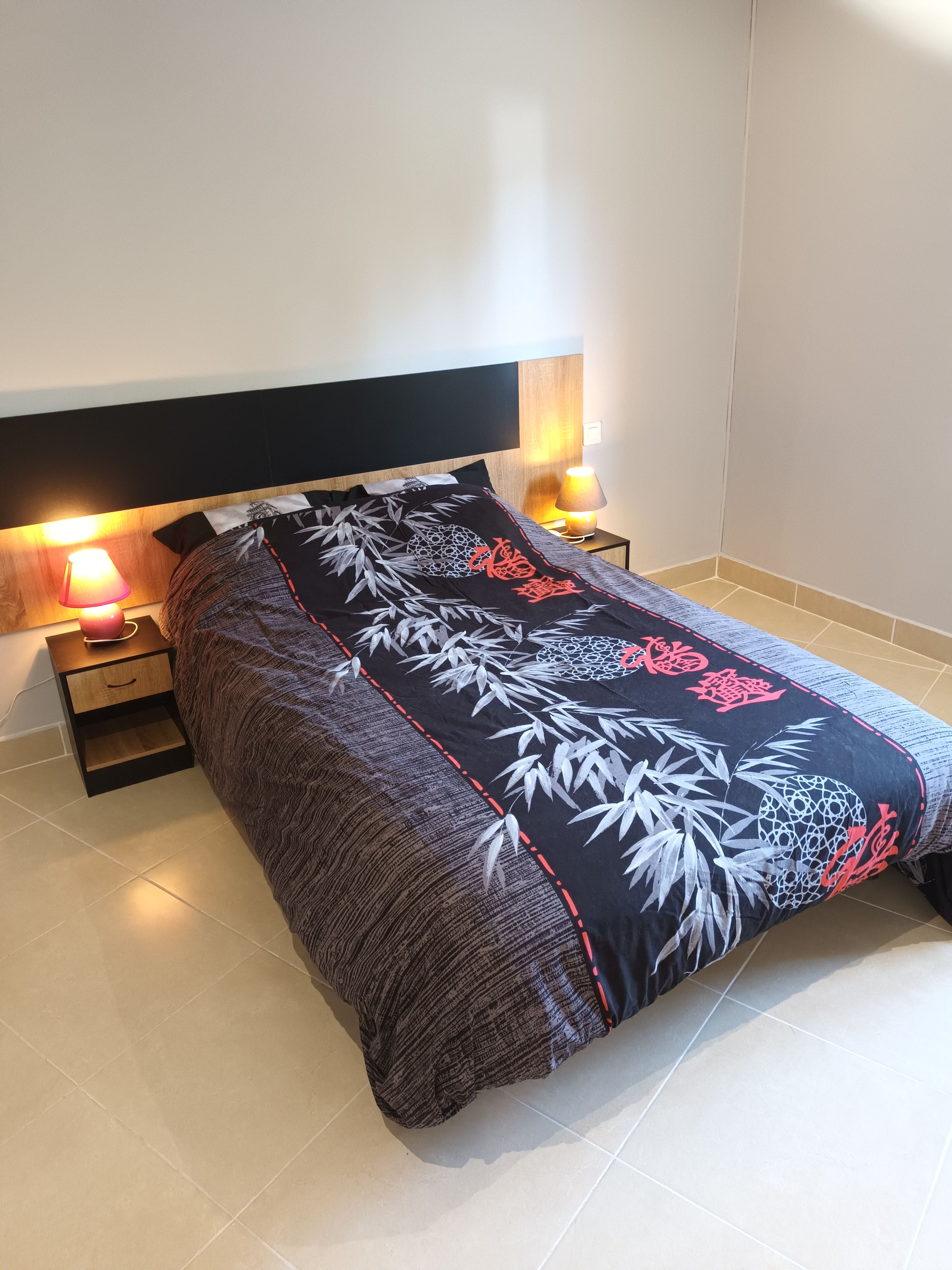 Un dormitorio con cama, mesitas de noche y lámparas.