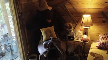 Un interior rústico con techo de madera, una silla de montar, una lámpara y una cama con una colcha.