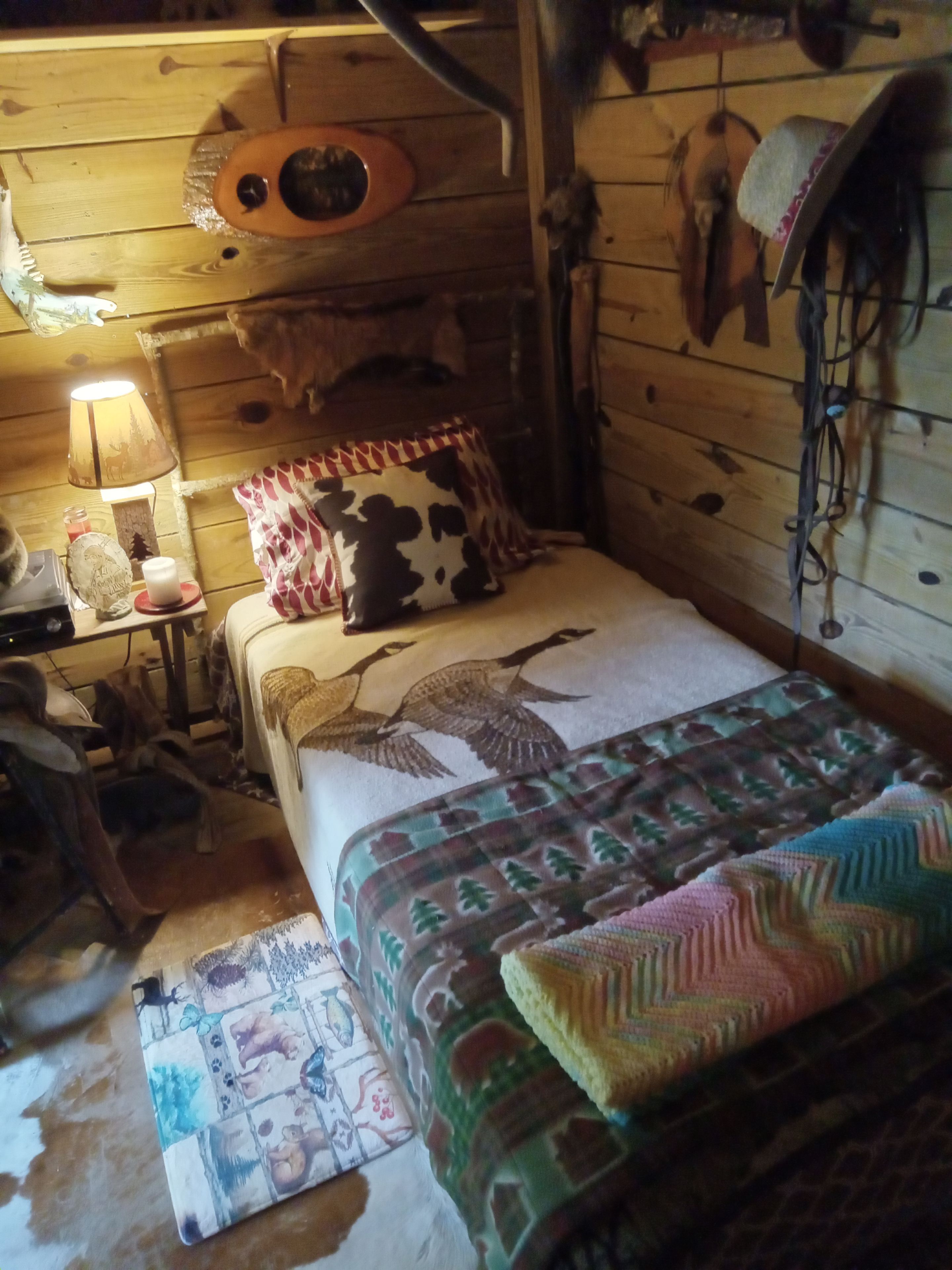 Une chambre confortable dans un chalet, avec un lit, une lampe et un mur décoré de motifs animaliers.